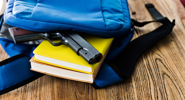 A handgun on top of books inside a backpack. 
